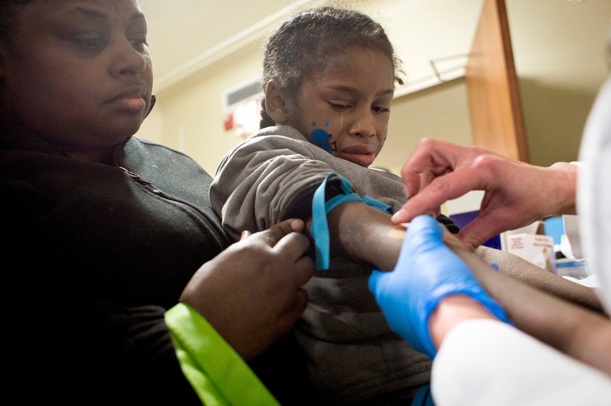 A small boy cries as medical staff takes a blood sample