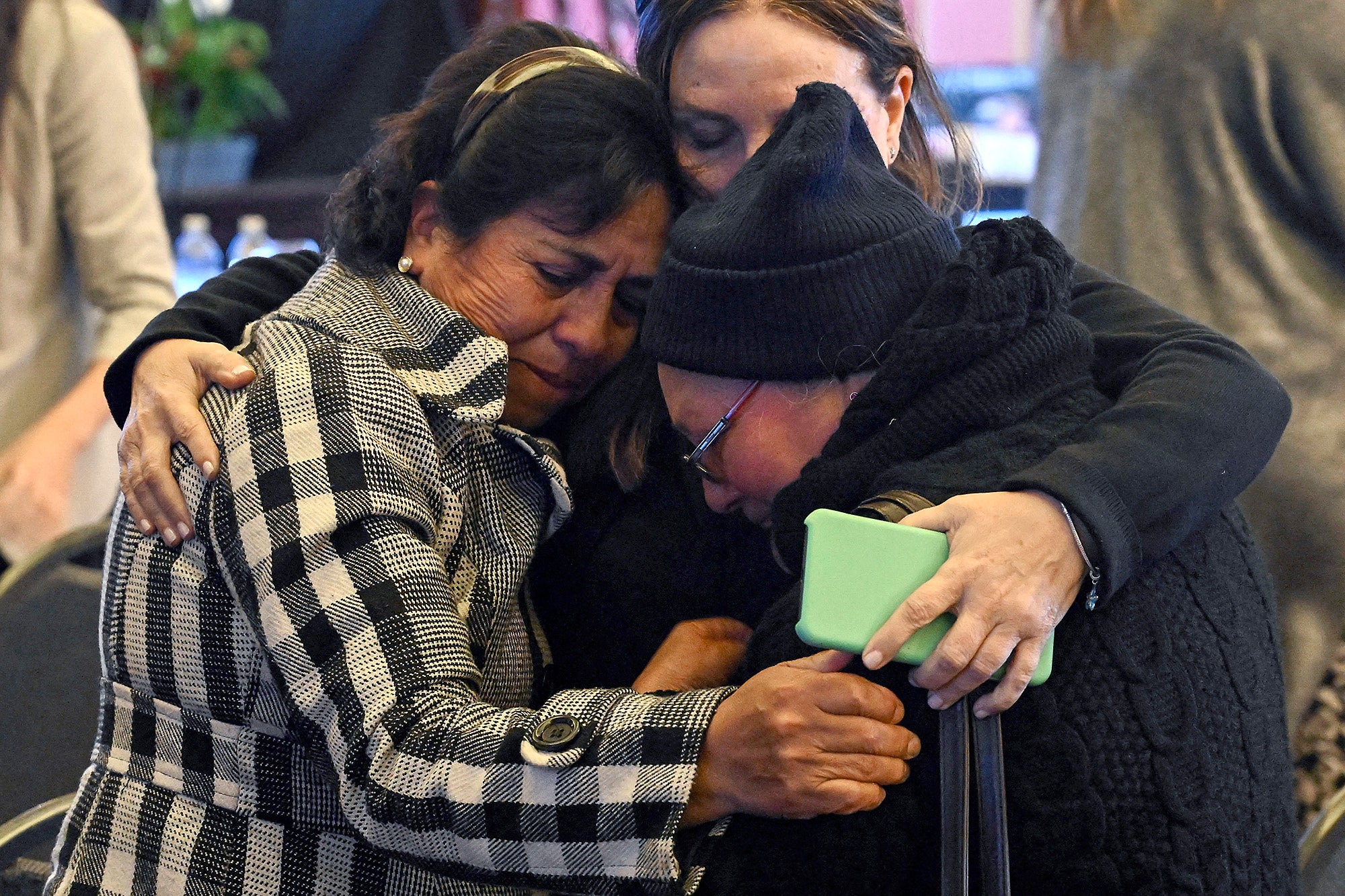 Three women share an emotional hug.