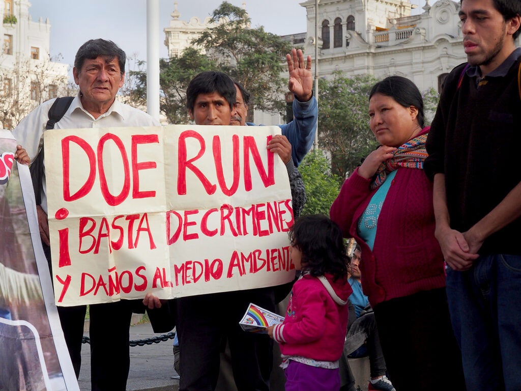 Residents of La Oroya, Peru, hold a sign that reads "Doe Run, it is enough of environmental crimes" during a march through the streets of Lima demanding medical assistance and a halt to the pollution generated by mining in Peru. (Fotoholica Press / LightRocket via Getty Images)