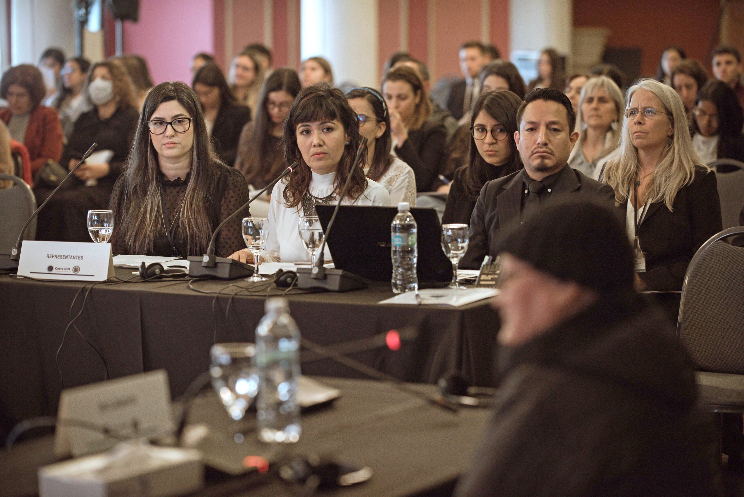 people watch testimony in a full court room.