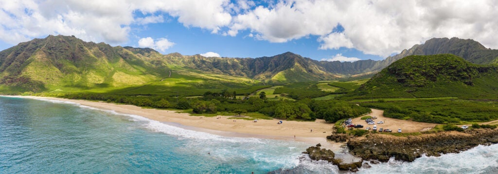 A wide landscape areal photo of a beach and large green valley.