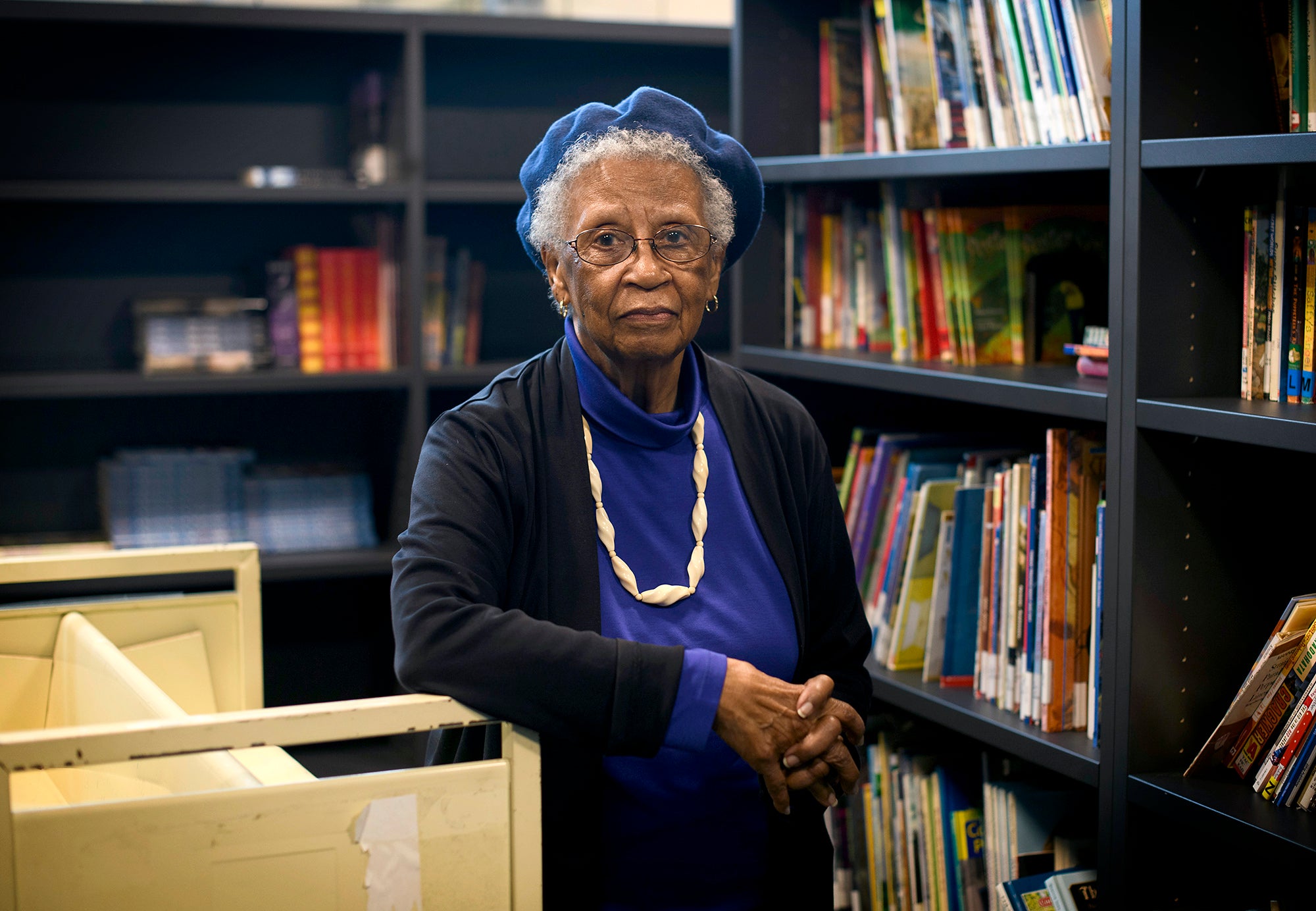 An older woman looking directly at the camera in a library.