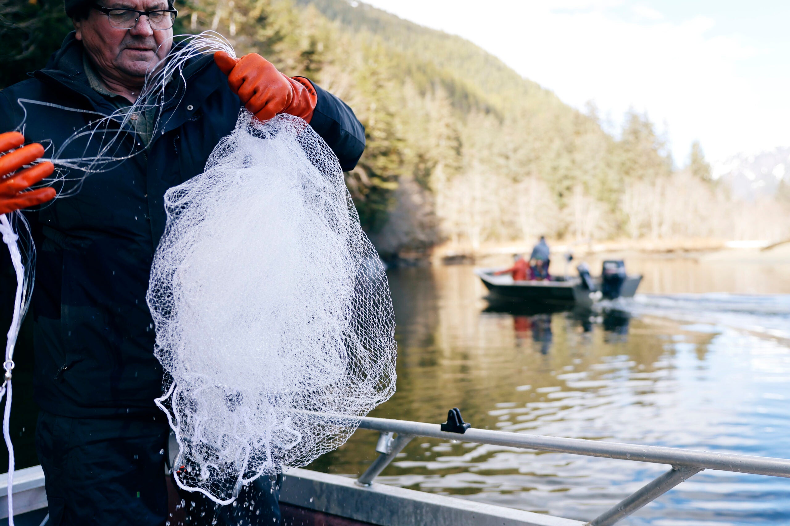 Man holds fishing cast on a boat on a river.