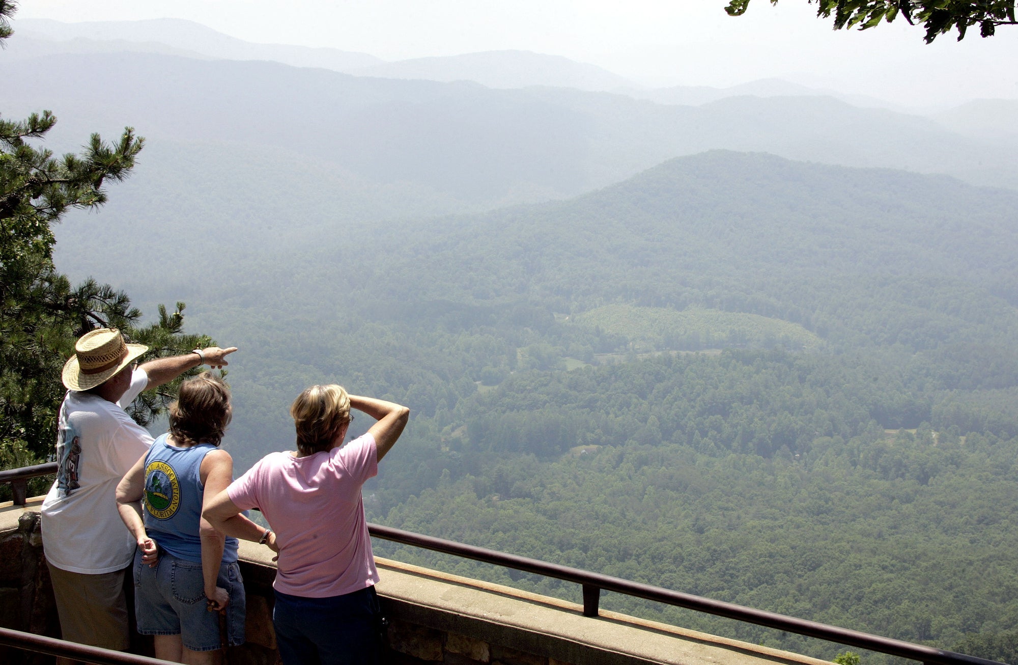 Three people look out on a very hazy valley