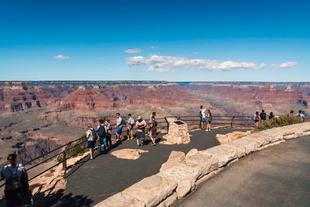 People gather on a railed lookout over the Grand Canyon.