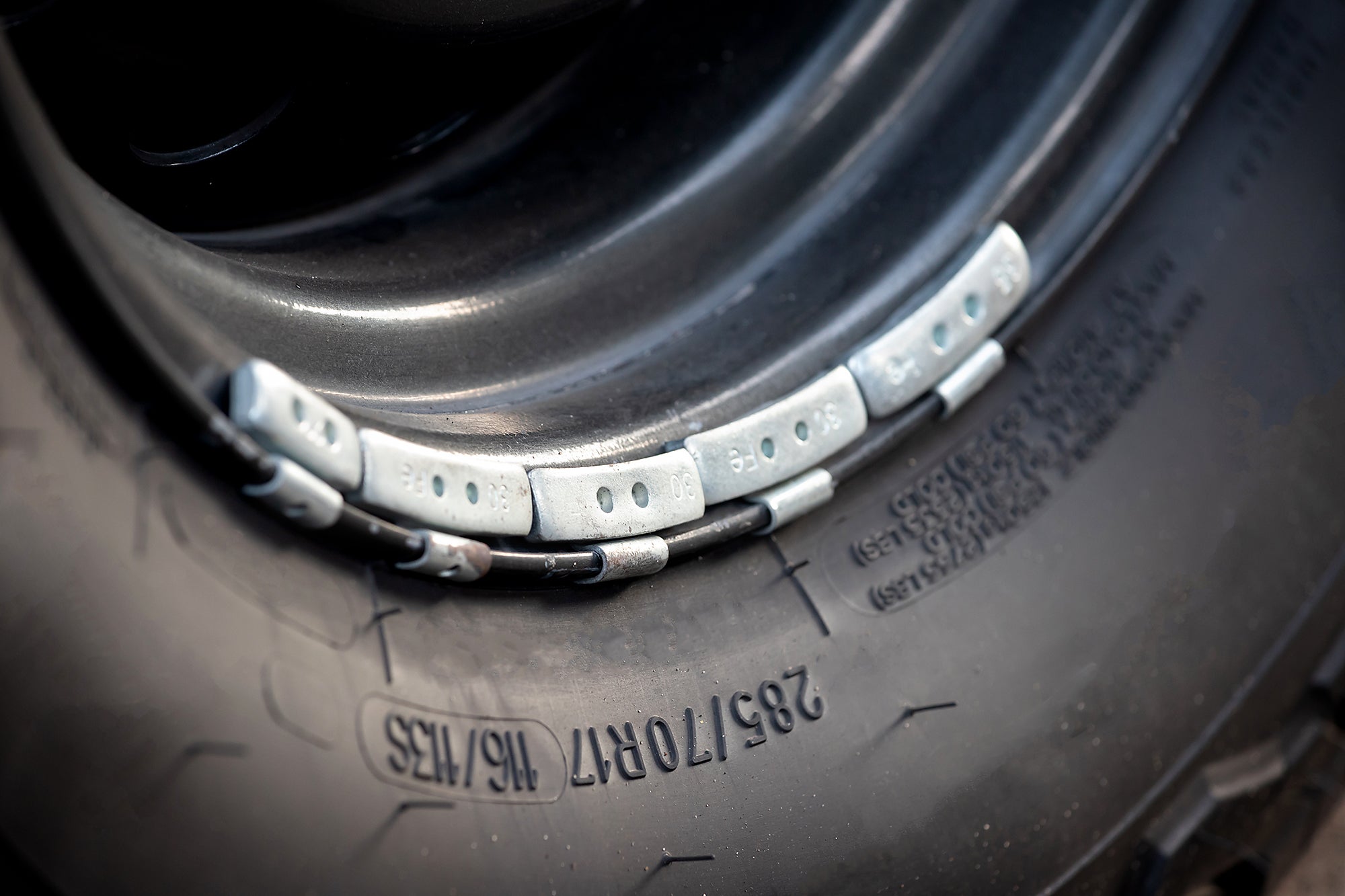 Light gray metal rectangle blocks attached to the rim of a car wheel, next to the tire.