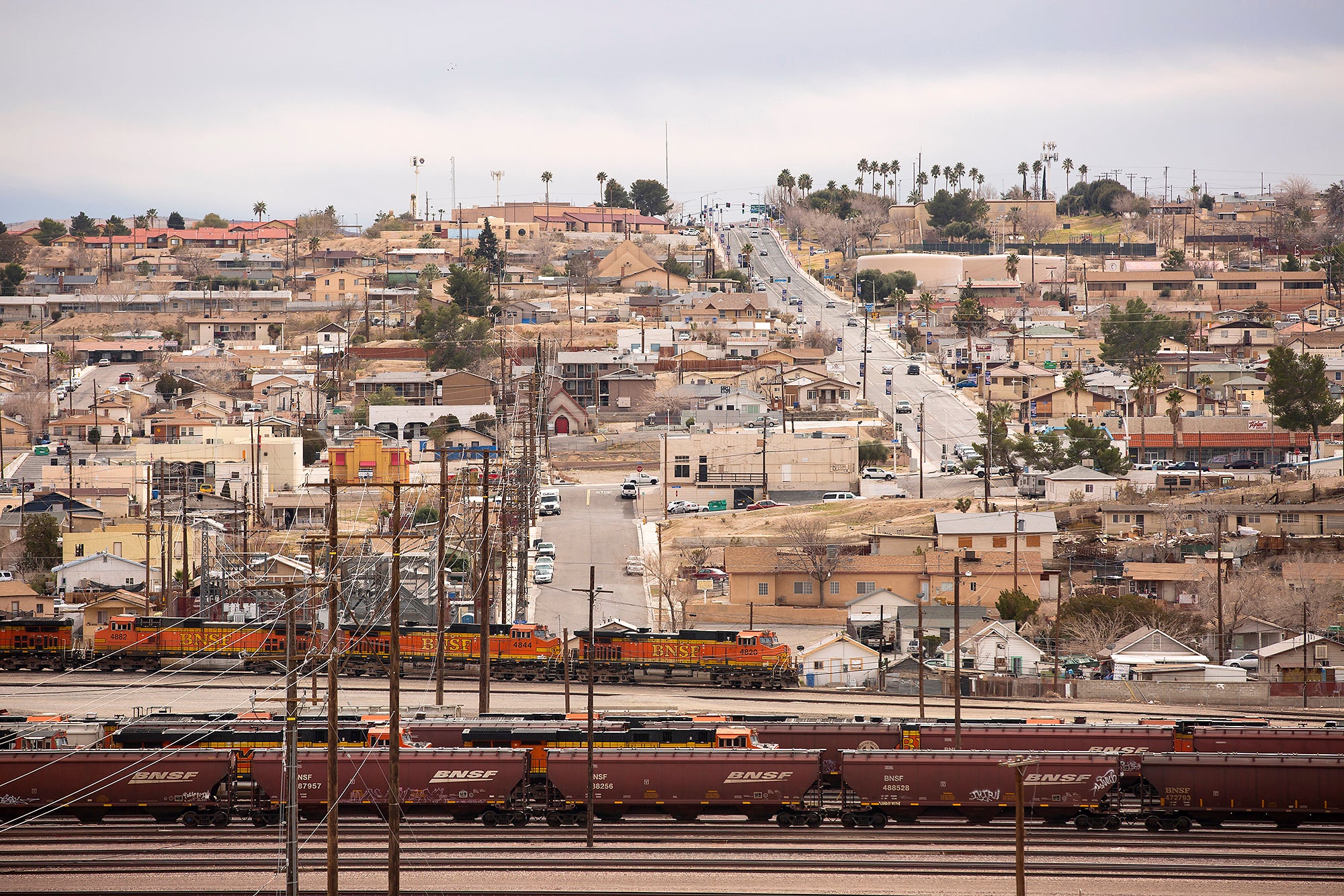 Trains in the foreground with homes and businesses rising on the hill behind.