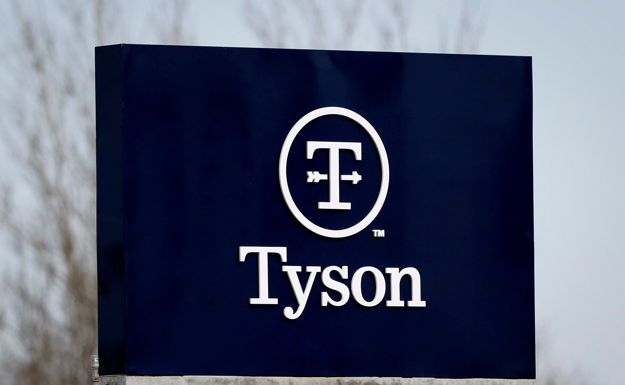 A blue outdoor sign with Tyson's name and corporate logo, a T with an arrow through it and circle around them.