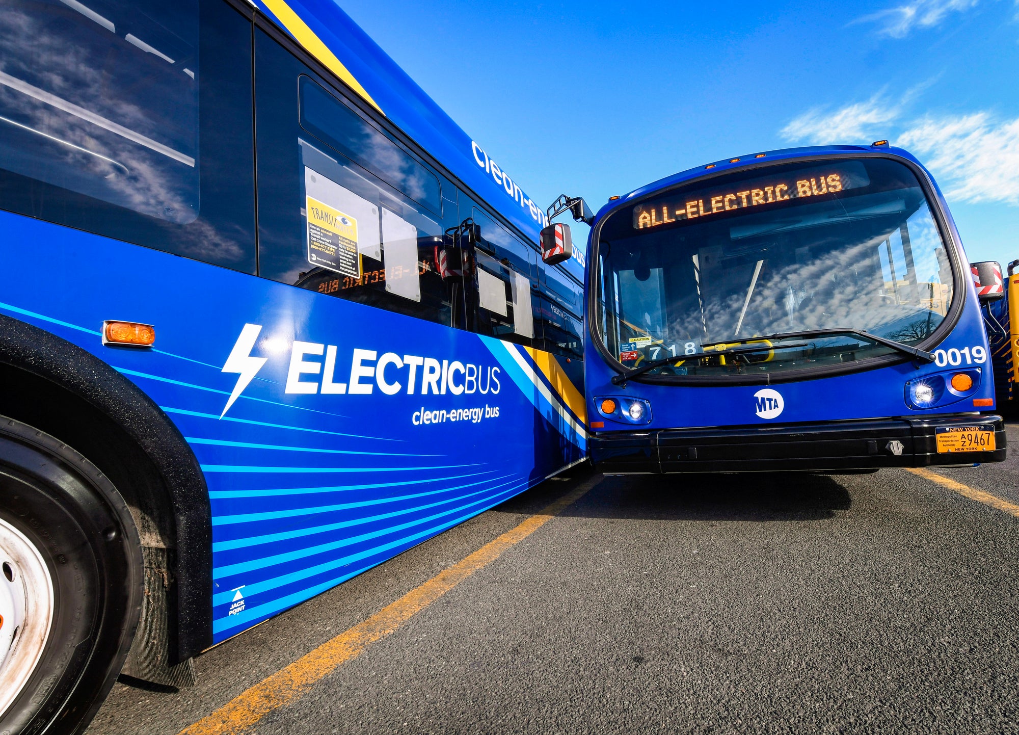 Two blue city buses next to each other. The side of one reads "electric bus clean-energy bus"