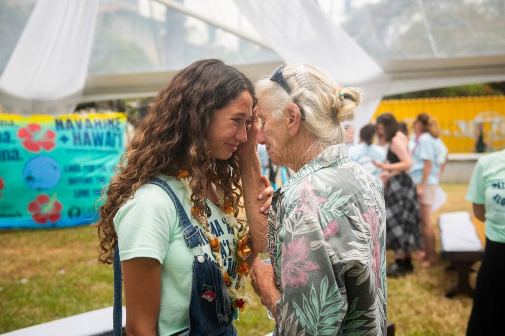 Youth plaintiff Kalā W. shares an emotional moment with an elder  on Jun. 24, 2024, during the celebration of the historic settlement in <a href="https://earthjustice.org/feature/hawaii-youth-climate-lawsuit" class="a_color--white"><em>Navahine v. Hawaiʻi Department of Transportation</em></a>. (Elyse Butler for Earthjustice)