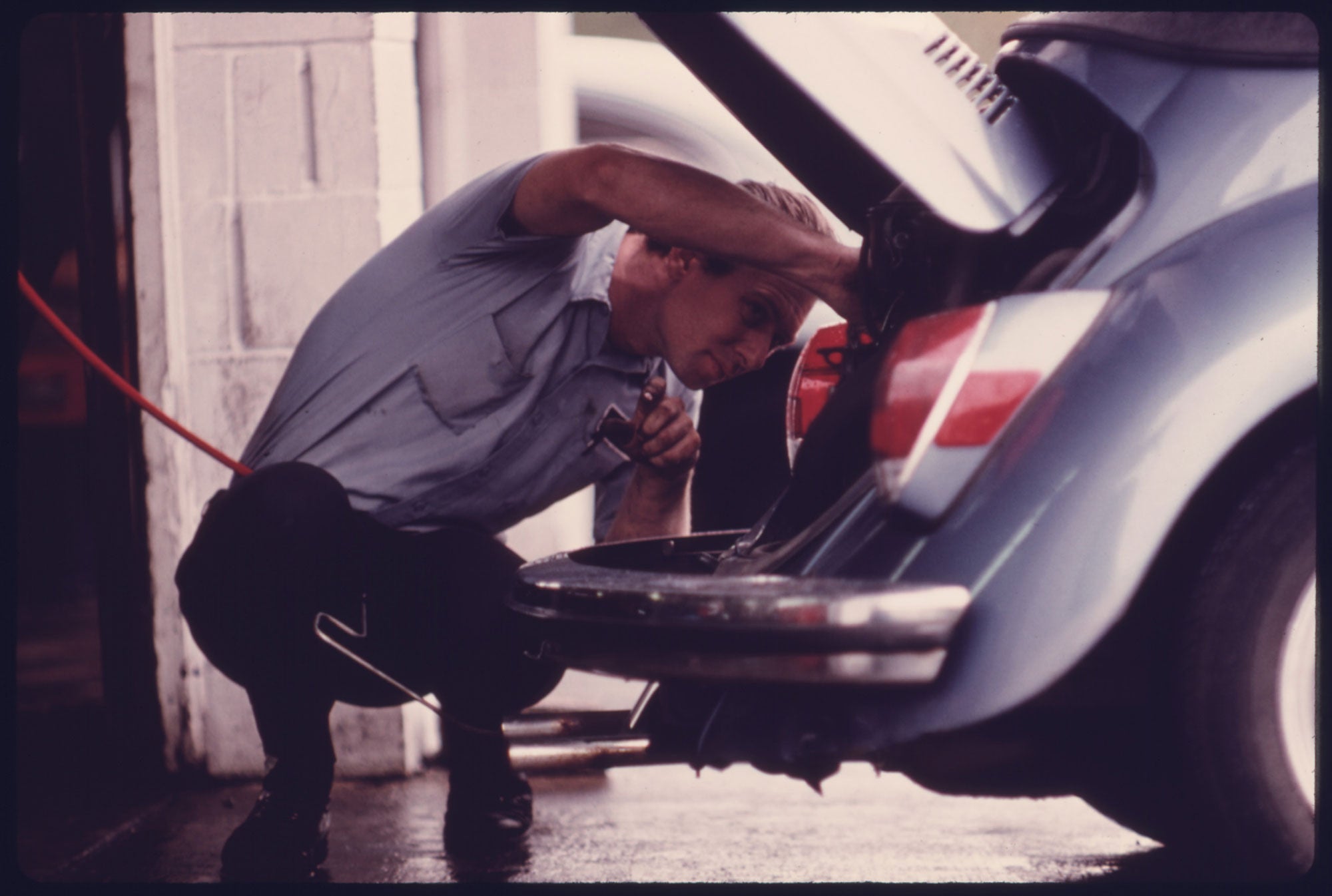 A service station mechanic adjusts the engine for a young woman whose vehicle had failed the emissions test at an auto emission inspection station in downtown Cincinnati, Ohio, in Sept. 1975.