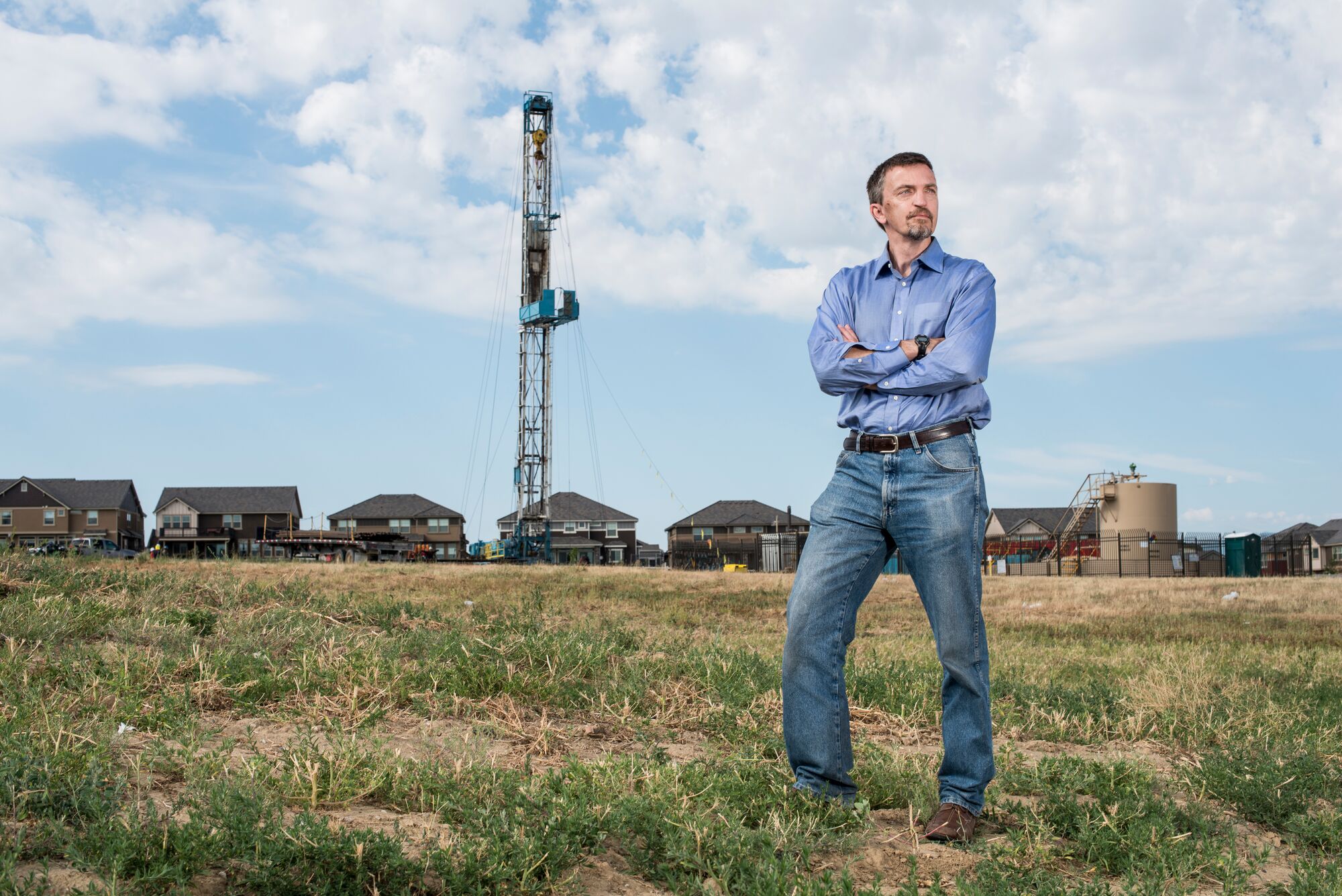 Earthjustice attorney Mike Freeman standing with arms crossed in front of an oil rig in Erie, Colorado, Monday, July 31, 2017.