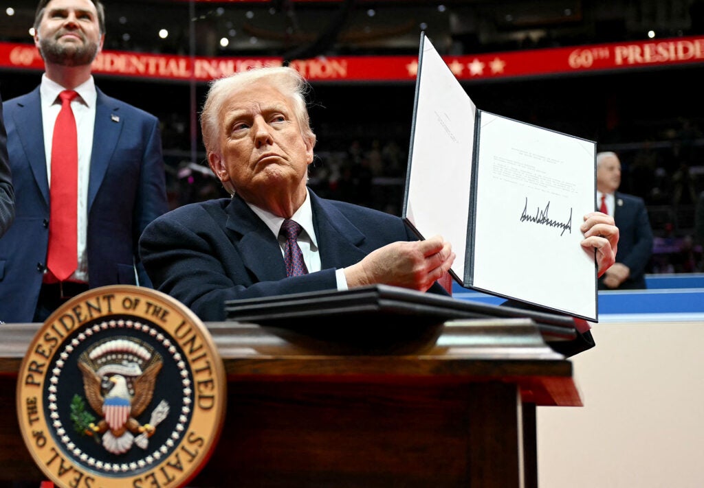 President Donald Trump holds a letter to the U.N. stating the U.S. withdrawal from the Paris Agreement during the inaugural parade inside Capital One Arena, in Washington, D.C., on Jan. 20, 2025. (Jim Watson / AFP via Getty Images)