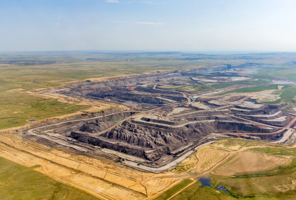 An aerial view of a large coal mine on the surface of a large, flat plain of land.