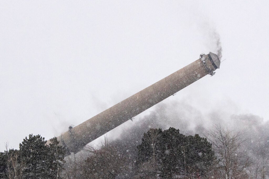 Debris and smoke fills the sky during the demolition of the Board of Light and Power's coal-burning J.B. Sims Generating Station in Grand Haven, Michigan. (Cory Morse / The Grand Rapids Press via AP)
