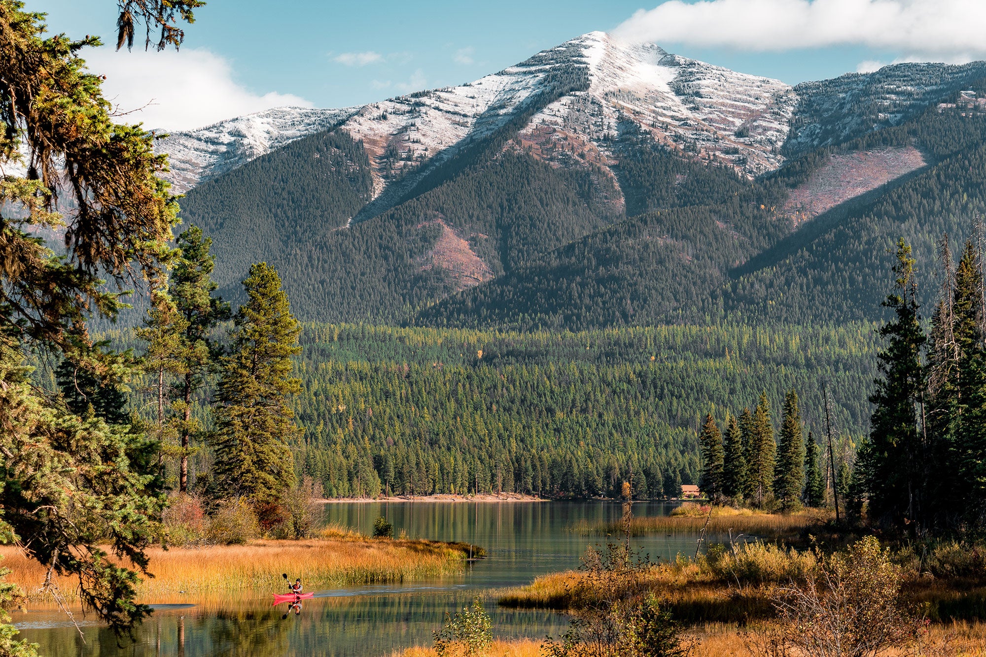 Flathead-National-Forests_2000x1334 Snowcapped mountains in the background. Green forest in the foreground with bodies of water.