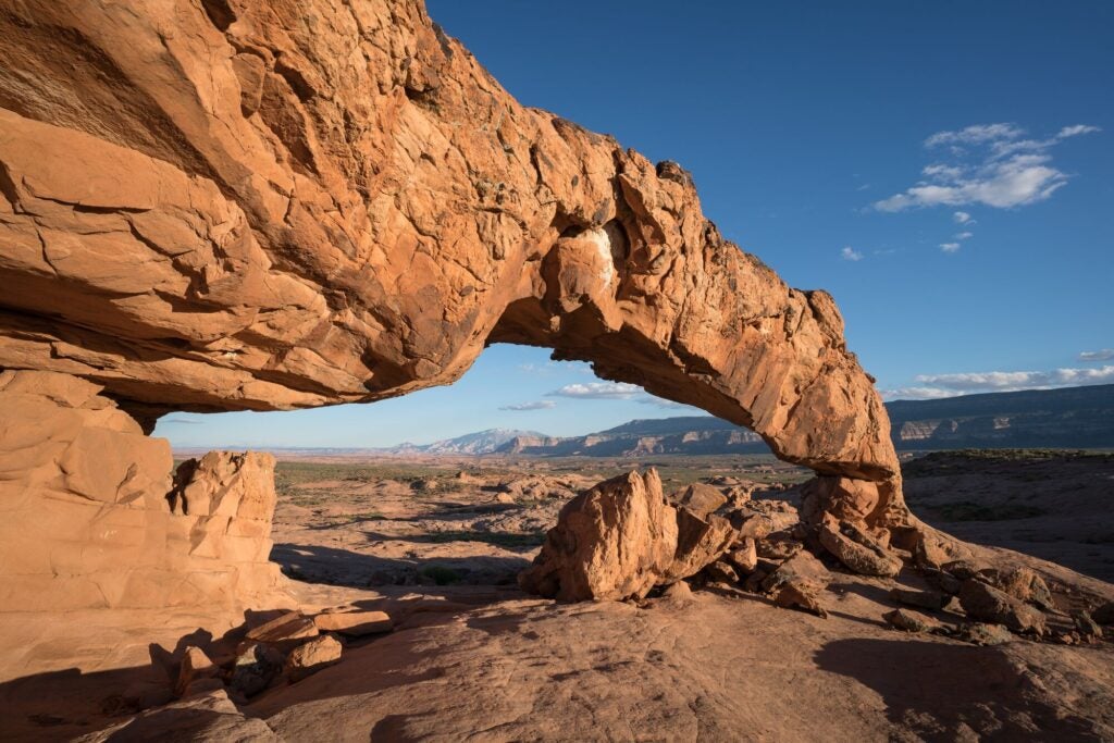 A large stone archway in the foreground with an expansive desert landscape in the background.