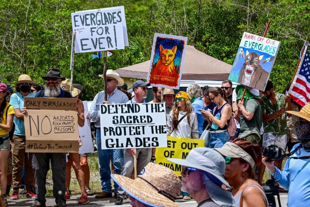 Manifestantes sostienen carteles mientras protestan contra la construcción de un centro de detención de inmigrantes en los Everglades, cerca de Ochopee, Florida, el 28 de junio de 2025. Debido a que se están utilizando fondos de FEMA para el centro de detención de Everglades, la ley exige que se realice una evaluación ambiental federal para proteger la fauna silvestre en peligro de extinción. (Giorgio Viera / AFP vía Getty Images)