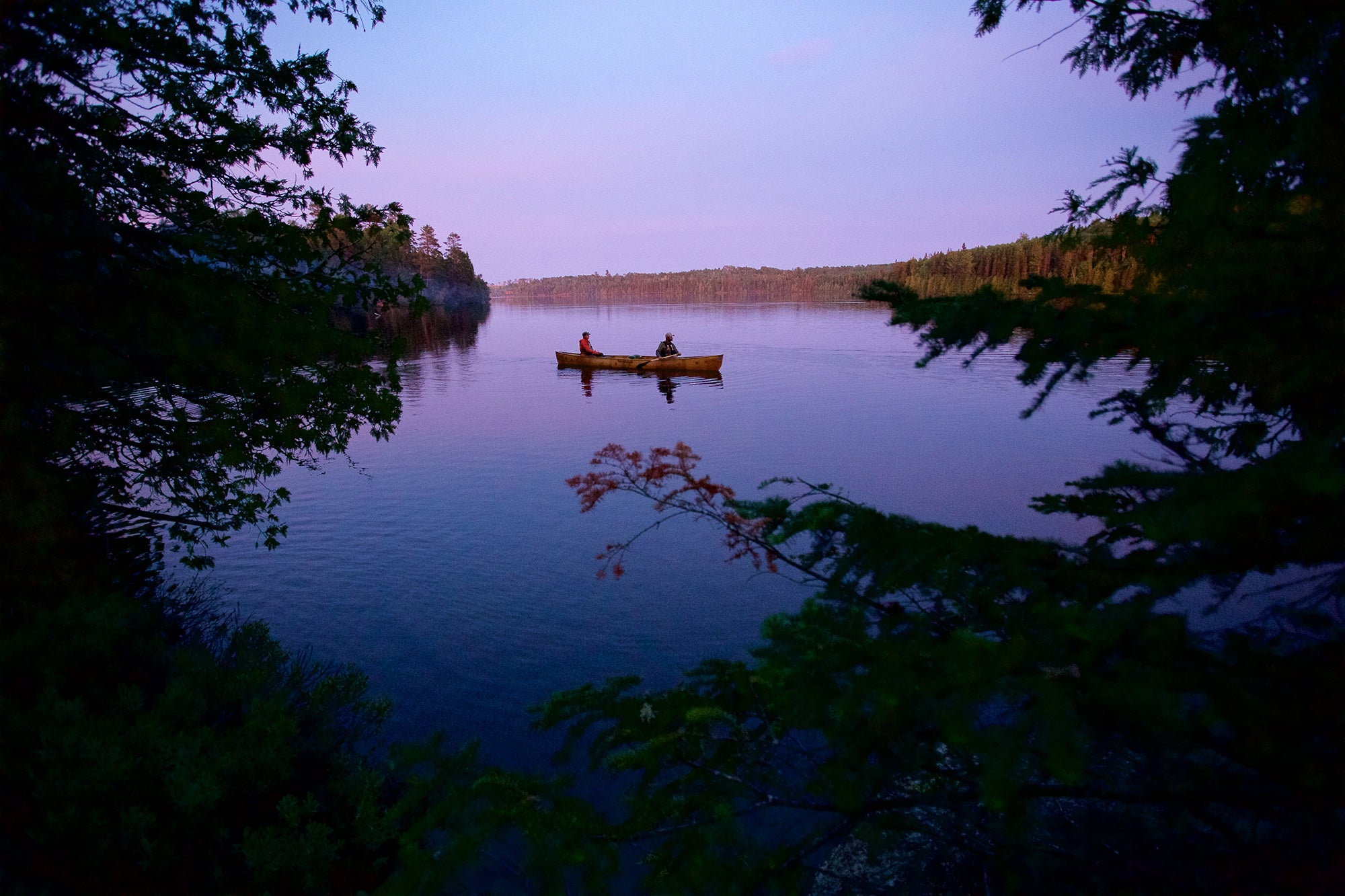 Two people in a canoe on still waters during twilight in the Boundary Waters Canoe Area in Northern Minnesota.