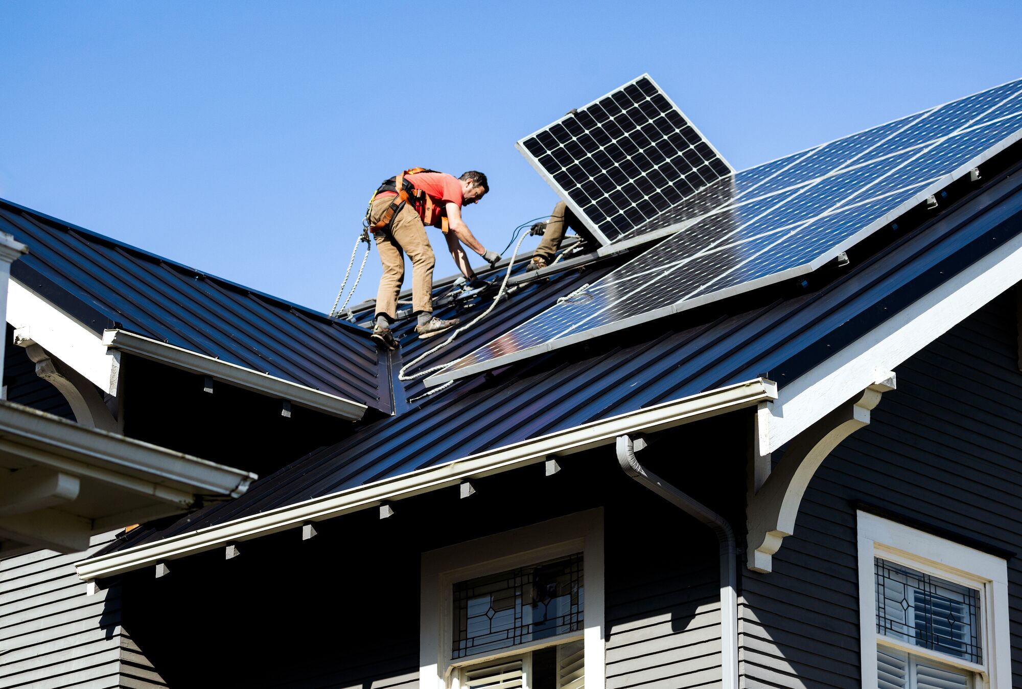 Two people on the roof of a home install solar panels.
