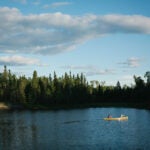 Two people paddle a canoe through the Boundary Waters Canoe Area Wilderness in Northern Minnesota.