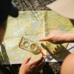 Two people lean over a map of the Boundary Waters Canoe Area Wilderness, pointing to a compass on the map.