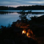 Embers leap out from a metal grate over a campfire as darkness descends in the Boundary Waters Canoe Area Wilderness.