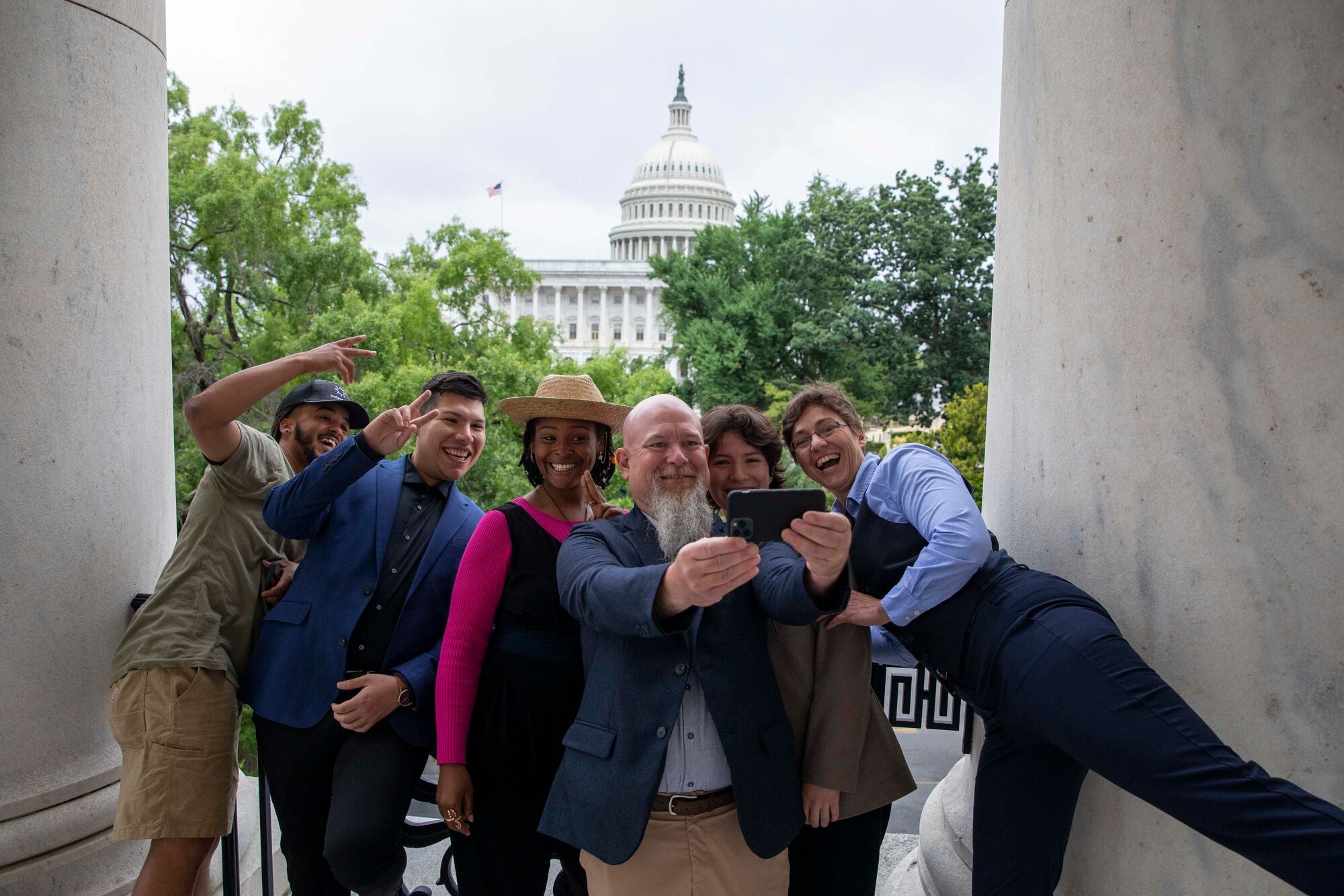 Farm Bill 2023 Lobby Day on Capitol Hill A group of smiling, laughing people lean in closely together between two large marble columns to take a selfie in front of the U.S. Capitol building.