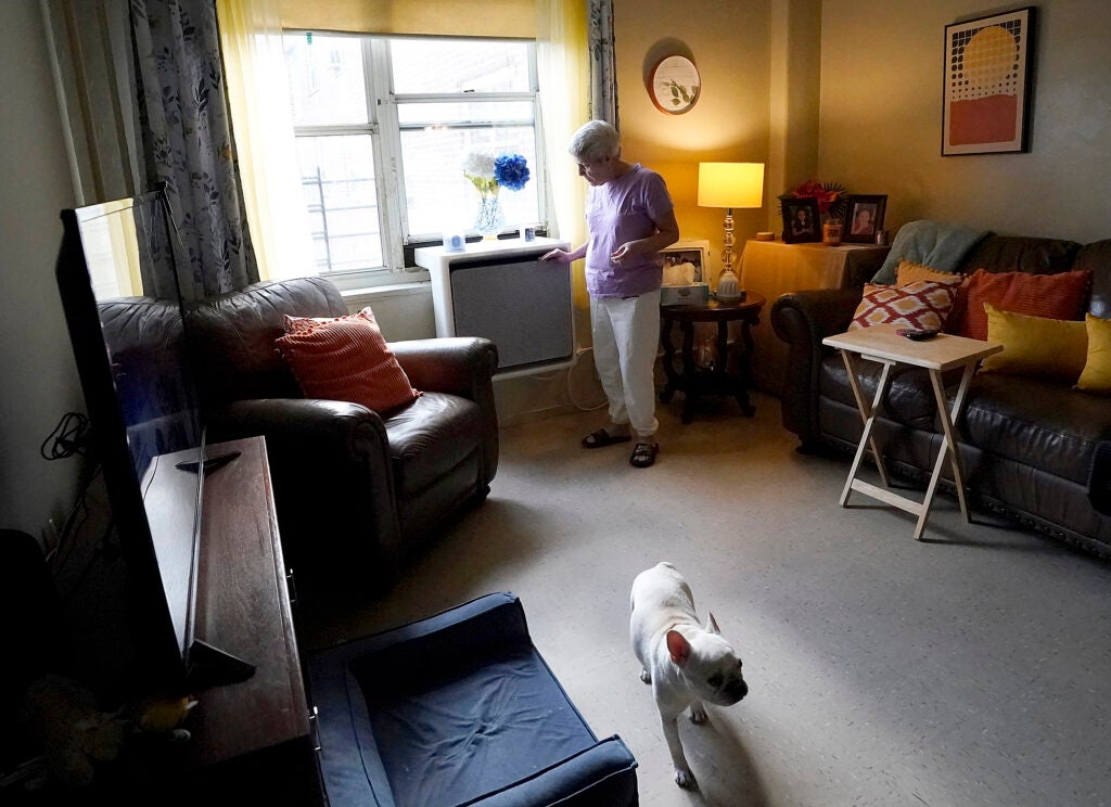 Regina Fred touches one of her window-mounted heat pumps in her apartment in the Queens borough of New York. (AP Photo)