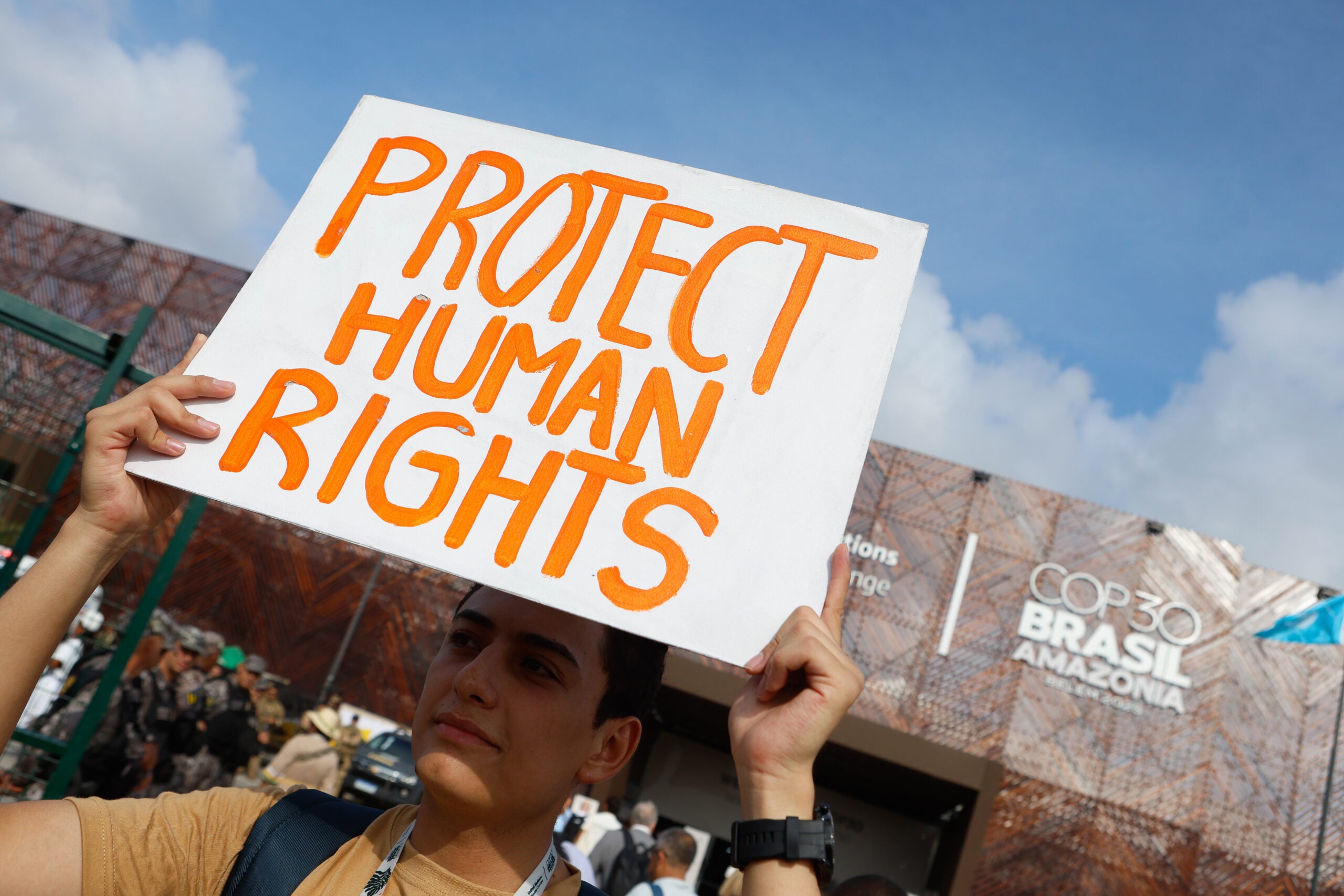 A man holds a sign that says "Protect Human Rights" at a civil society demonstration at the COP30 in Belém, Brazil.