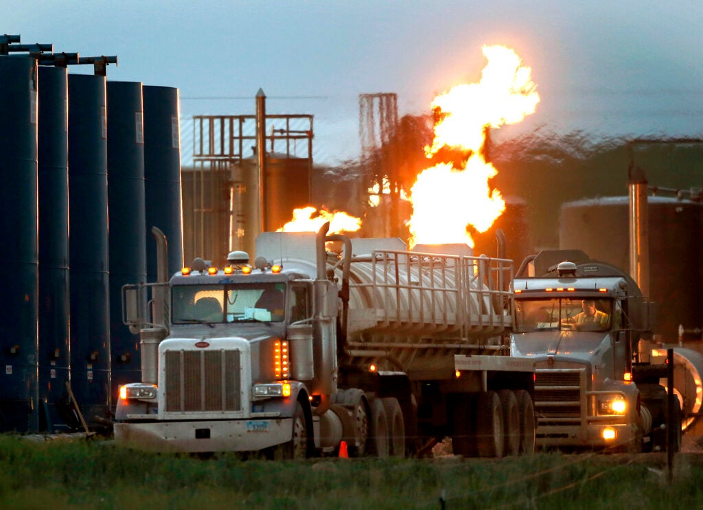 Truckers Movement for Justice Drivers and their tanker trucks capable of hauling water and hydraulic fracturing liquid line up near a natural gas burn off flame and storage tanks in Williston, North Dakota. (Charles Rex Arbogast / AP)