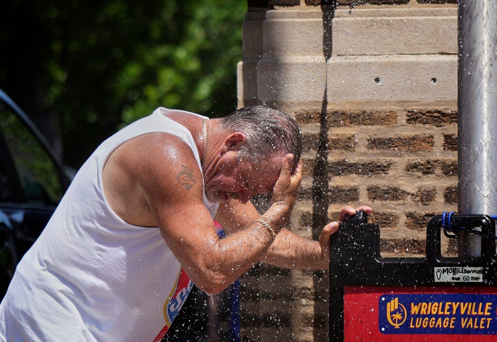 A man cools off under a sprinkler provided by the Chicago Fire Department during hot weather in the city on June 22, 2025. (Nam Y. Huh / AP)