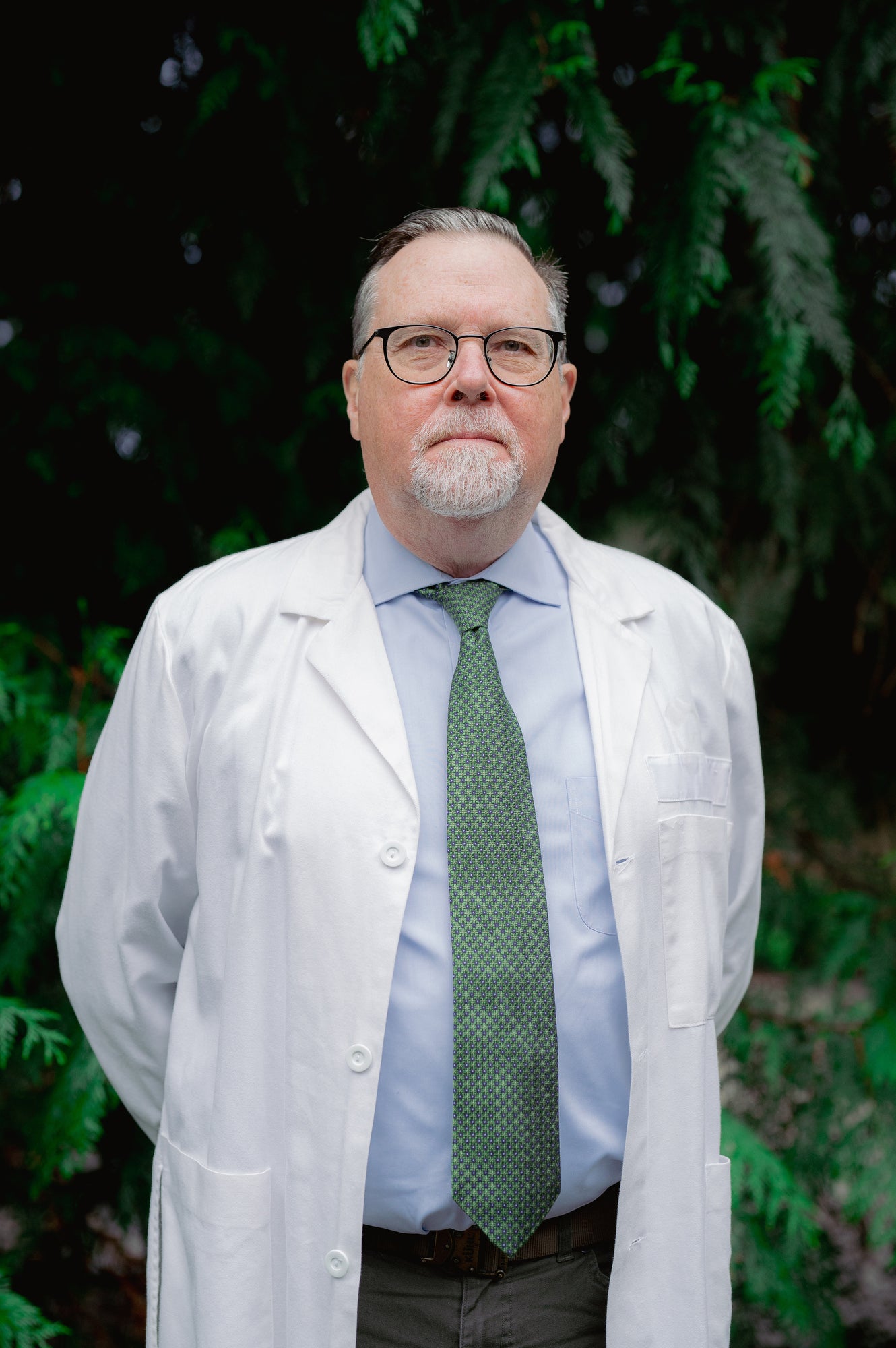 A portrait of a man looking at the camera and wearing a white doctor's coat.