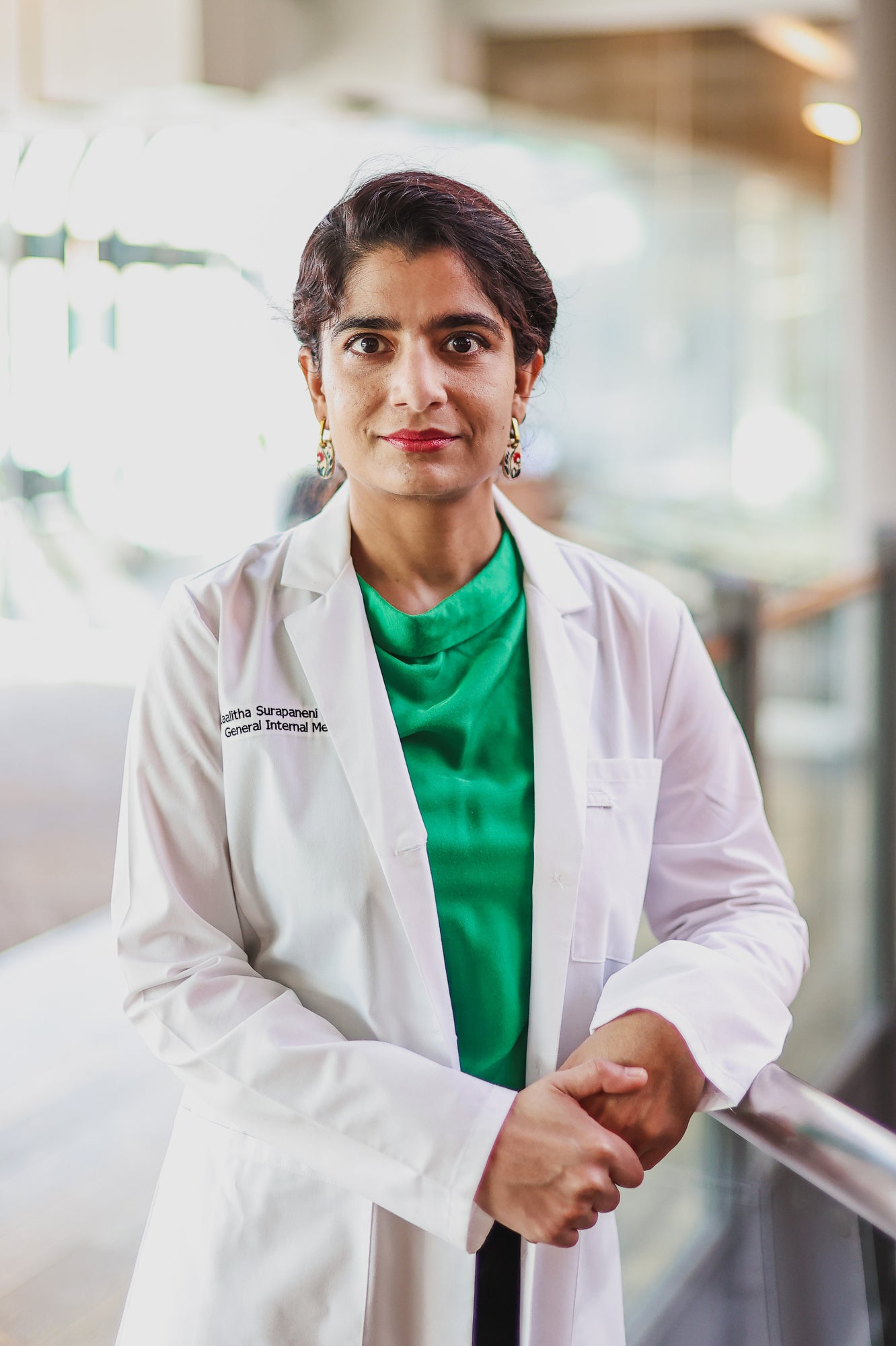 A woman wearing a doctor's coat looks directly in the camera for a portrait.