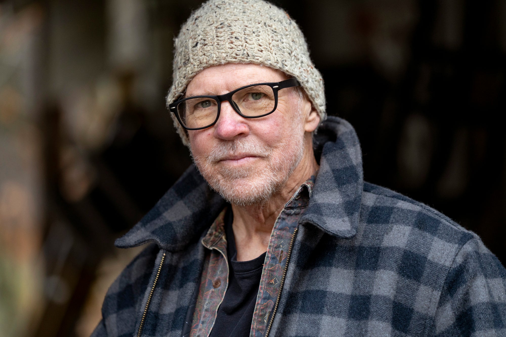 A man wearing a jacket and stocking cap looks directly into the camera for a portrait.