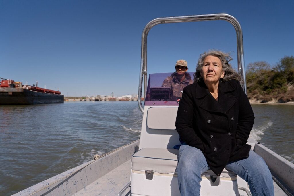 Diane Wilson rides in a boat, surveying the land and water for areas where plastic pellets might be found in Seadrift, Texas.