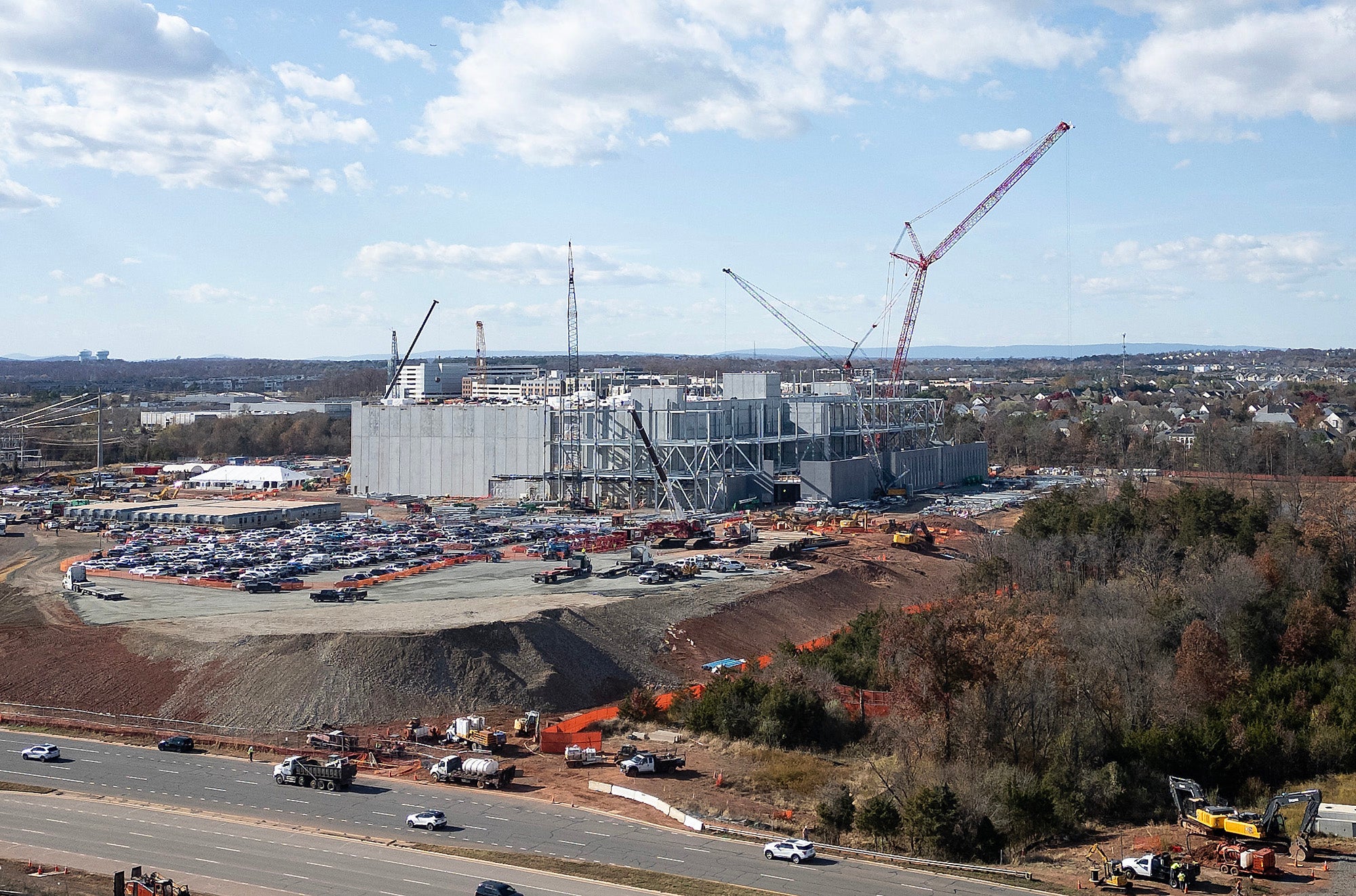 A large building is under construction with homes visible behind it.