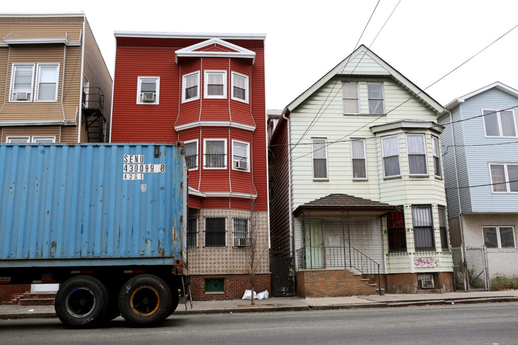 A row of close townhouse homes with part of a shipping container on a truck bed is seen in front of them.