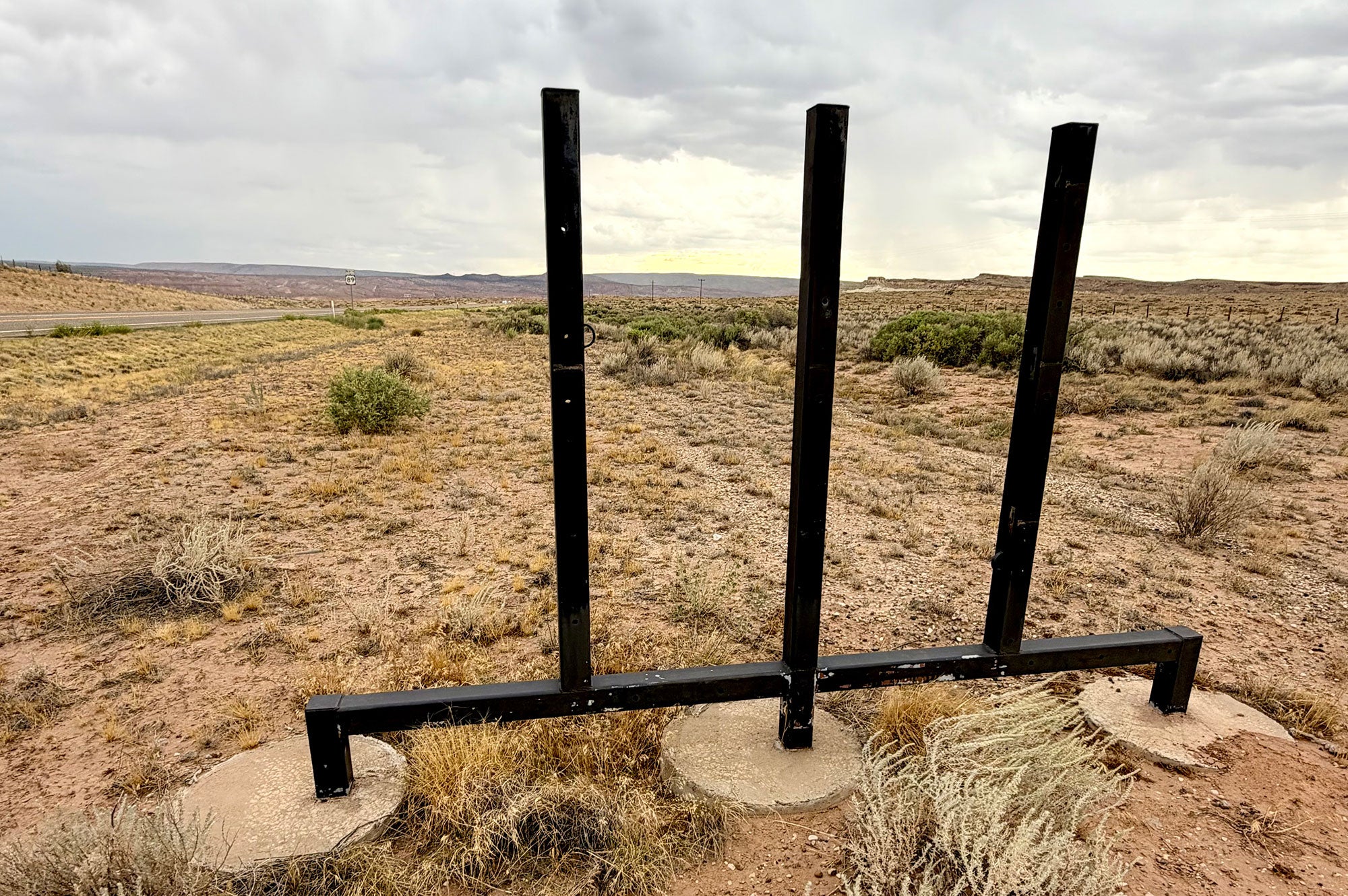 An expansive landscape is visible through an empty metal scaffolding frame that used to hold a large sign.