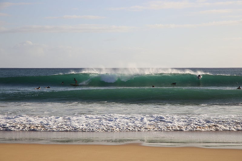 Swimmers and surfers ride the waves at Kekaha Beach in West Kauaʻi.