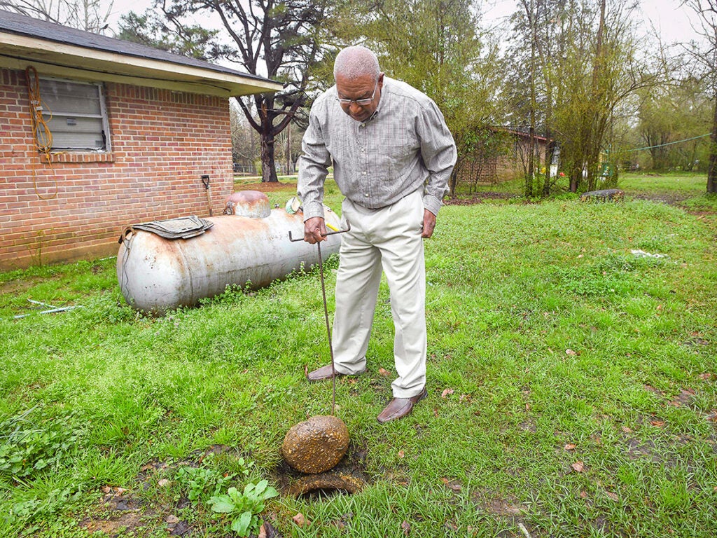 Lowndes County resident Jerome Means examines the failing wastewater sanitation system at his home in Hayneville, Ala. in 2019.
 (Julie Bennett / AP Photo)