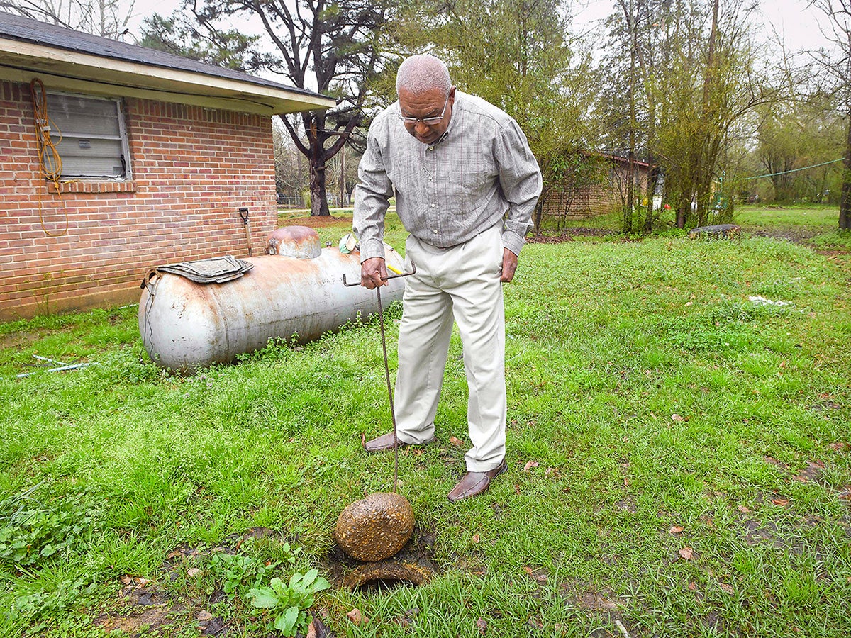 Lowndes County resident Jerome Means examines the failing wastewater sanitation system at his home in Hayneville, Ala. in 2019.