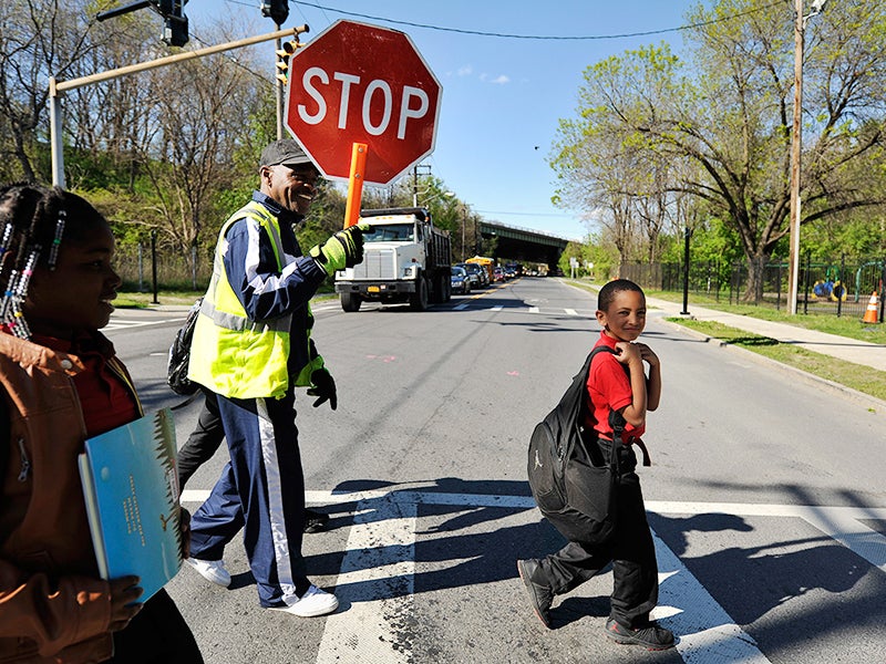School crossing guard Be Be White stops traffic on South Pearl Street for children, including his son Brayton and Sanaiya, both six years old. White, who has lived in Ezra Prentice Homes for 12 years is among the residents who attended meetings against th