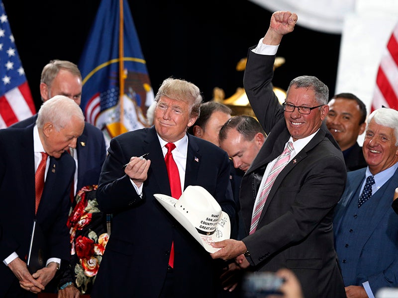 President Donald Trump signs the hat of Bruce Adams, chairman of the San Juan County Commission, after signing a proclamation to shrink the size of Bears Ears and Grand Staircase Escalante national monuments.