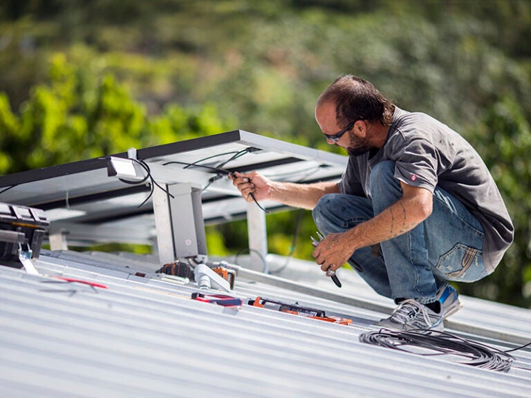 A technician installs a solar energy system at a home in Adjuntas, Puerto Rico, in July 2018.