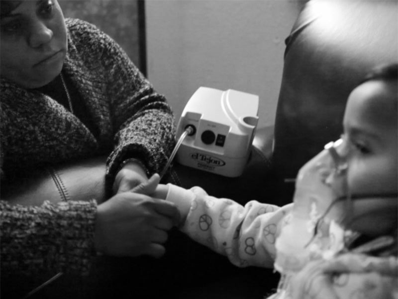 A mother watches over her child during treatment for asthma.