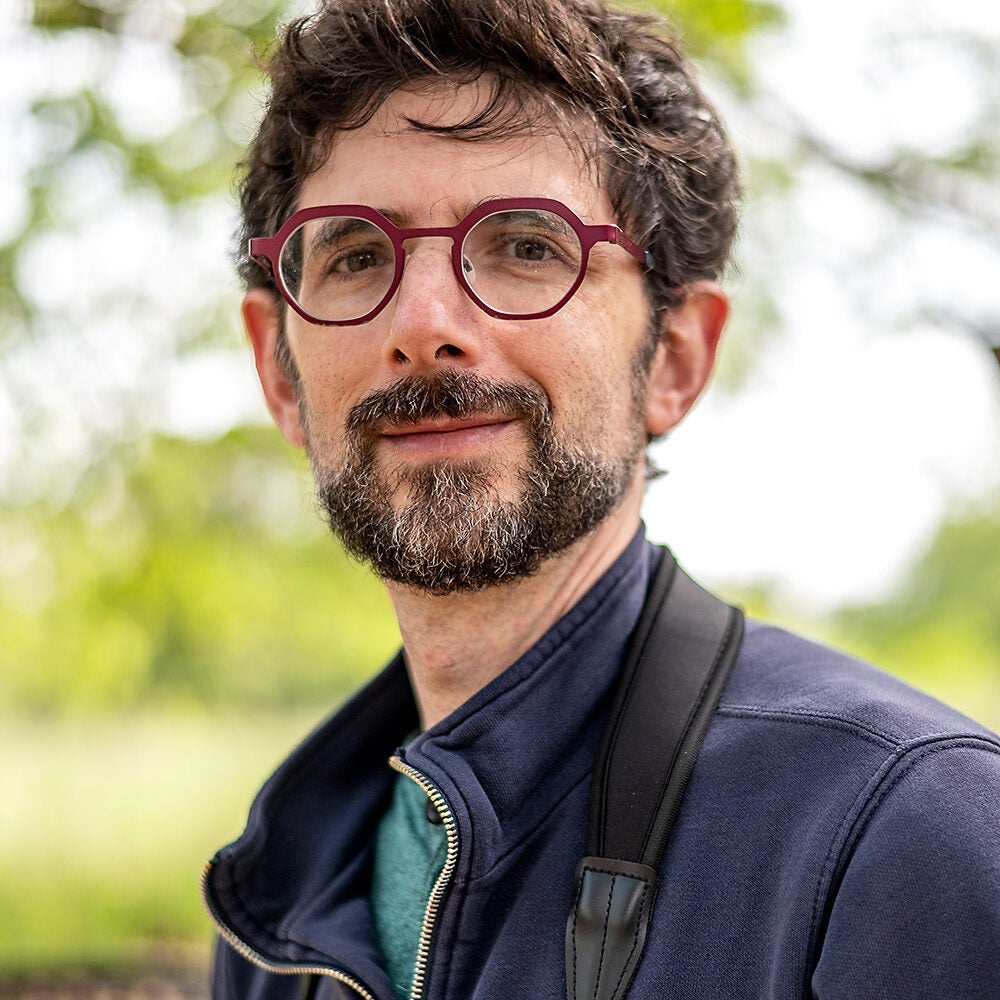 A bearded man with glasses looks into the camera.