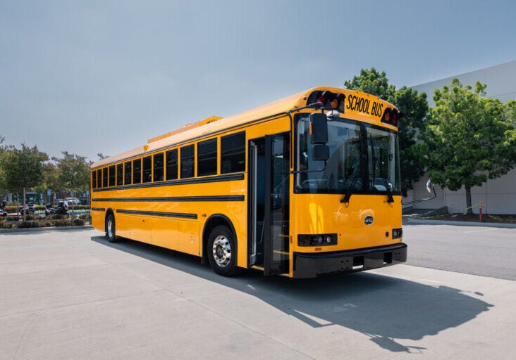 A new, yellow school bus in a parking lot.