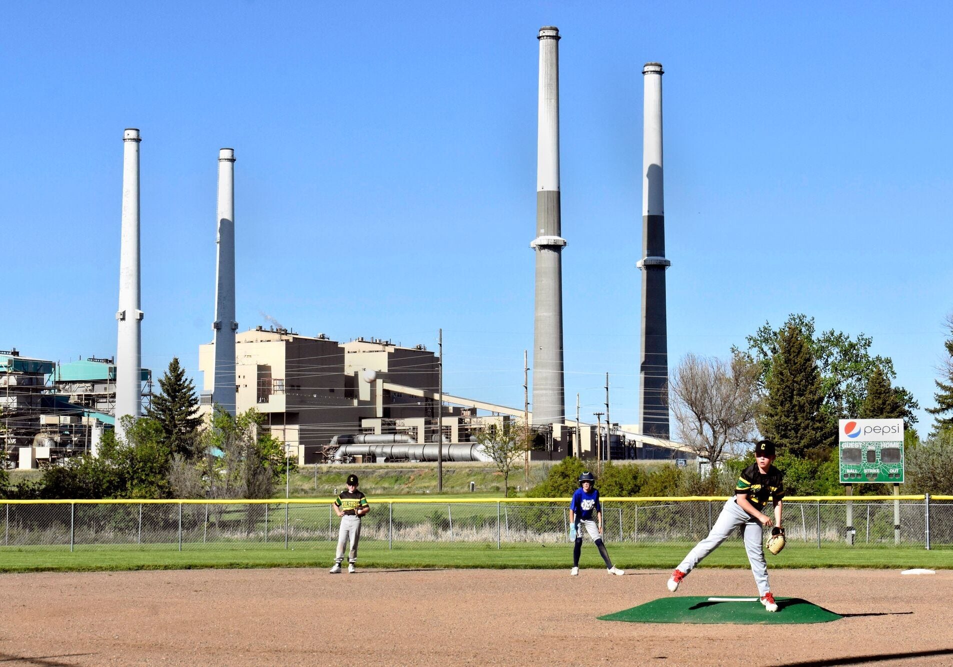 The coal-fired Colstrip Generating Station is seen behind youths playing baseball in Colstrip, Montana.