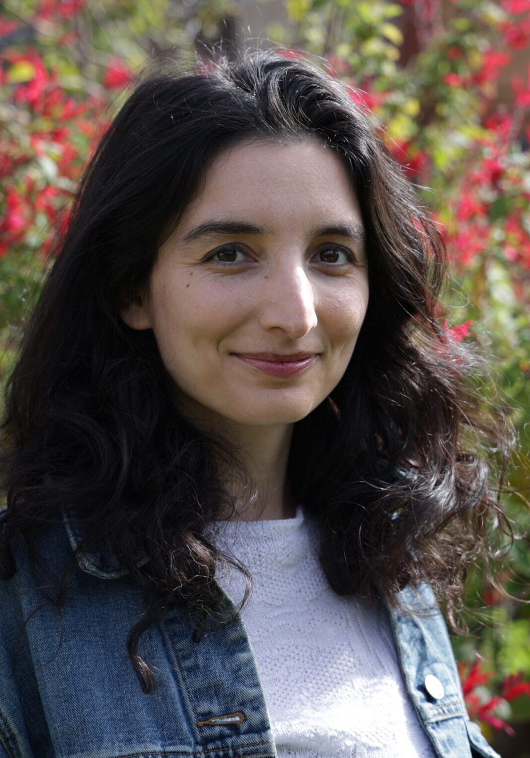Danika Desai, senior attorney with Earthjustice's Oceans Program, is set before a background of red flowers and greenery. She is smiling at the camera.